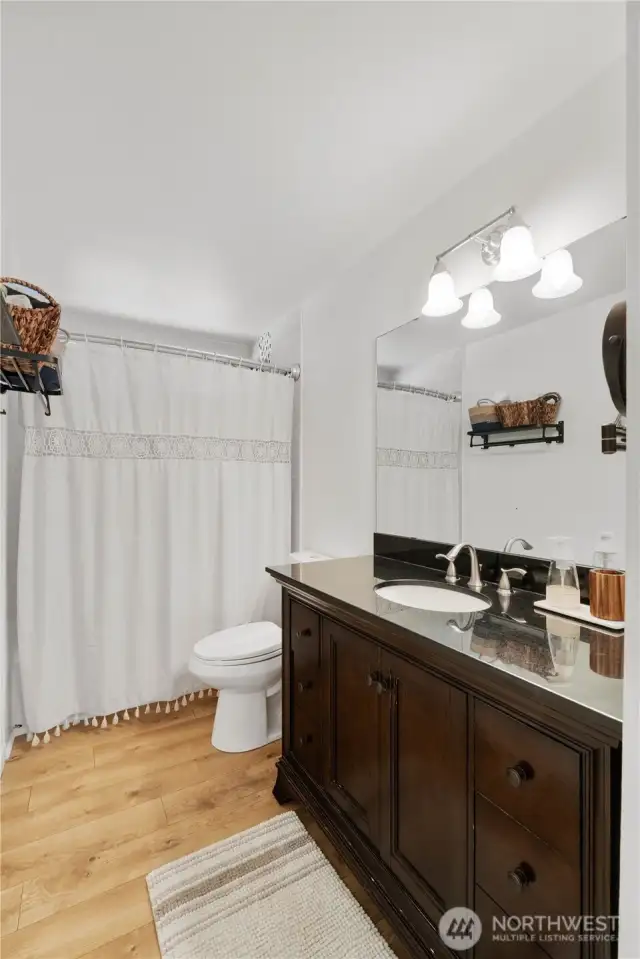 The refreshed bath includes a beautiful vanity with granite countertop, tile surrounded shower, laminate floor & newer toilet