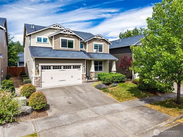 This front view shows off a home that’s as functional as it is beautiful. The wide driveway offers plenty of space for two cars, and the side gate access gives you easy entry to the backyard. A mature maple tree stands proudly between the sidewalk and street, offering shade and charm, while the blooming purple landscaping adds a pop of color to the front yard. With Hardiplank siding, you can rest easy knowing this home is built for durability and peace of mind.