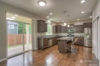 Cooking just got a lot more fun in this kitchen. With granite countertops, a generous kitchen island with seating, and beautiful shaker cabinets, this space is both elegant and practical. The tall ceilings give it a spacious, open feel, and the stainless-steel appliances, including the bottom freezer French door fridge with a water and ice dispenser, make meal prep a breeze. Two pendant lights over the island, plus canned lighting, provide the perfect ambiance, and the window over the sink gives you a glimpse of the backyard while you work. Not to mention the double-wide pantry for all your kitchen essentials.