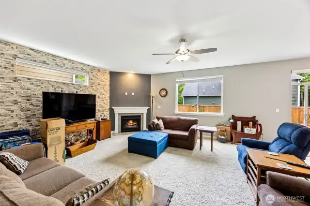 This family room just keeps getting better. With all the same cozy elements, accent wall, gas fireplace, and classic white mantle, this shot reveals the hidden genius of a long upper landscape window on that textured accent wall. It lets in even more light without sacrificing precious furniture placement. So go ahead, set up your couch under that window and bask in the glow, literally and figuratively. This room is not just functional, it's got that "I can’t wait to hang out here" vibe.