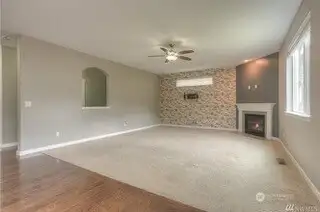 This family room is the heart of the home, with a striking full accent wall that adds a pop of texture and style. The darker accent wall behind the gas fireplace with its elegant tile surround and white mantle gives the room a touch of sophistication. The plush carpeting makes it cozy and inviting, while the large picture window overlooking the backyard brings the outdoors in. It’s a space designed for both comfort and conversation.