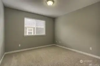 Simple and serene, this 4th bedroom is designed with the same neutral tones and white trim found throughout the home. The carpeting adds a soft, cozy touch, and the wide slat blinds let you control the light and privacy. Whether you need an extra bedroom, a home office, or a place to unwind, this room is the perfect blank canvas for whatever your needs may be.