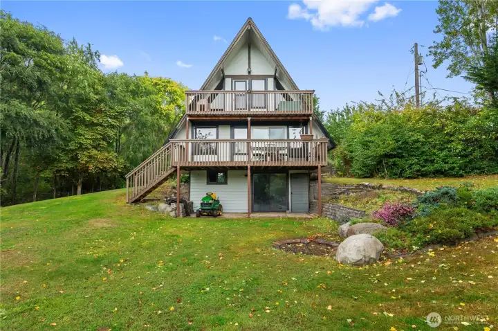 Light-filled open-beam design with a loft, flexible lower level, and deck overlooking fruit trees + greenhouse.