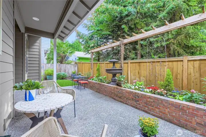 Let's call this a backyard oasis! Poured patio and brick planter hardscaping, partially covered, fully fenced, and the most beautiful turf-lawn all year round!