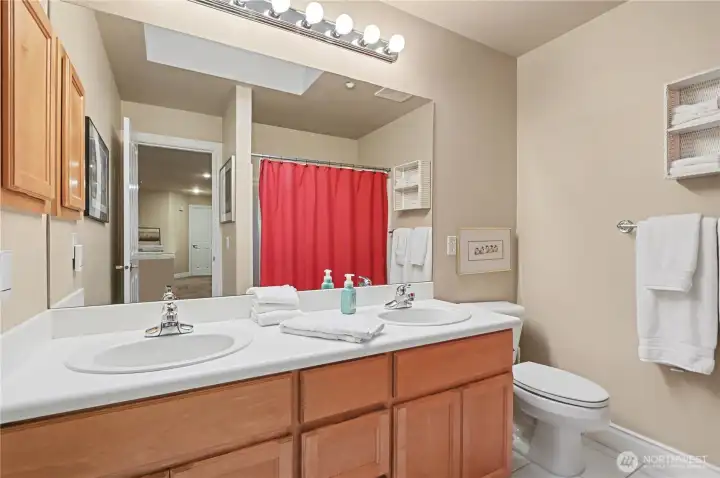 Full upstairs bathroom offers dual vanity and natural light from a skylight.