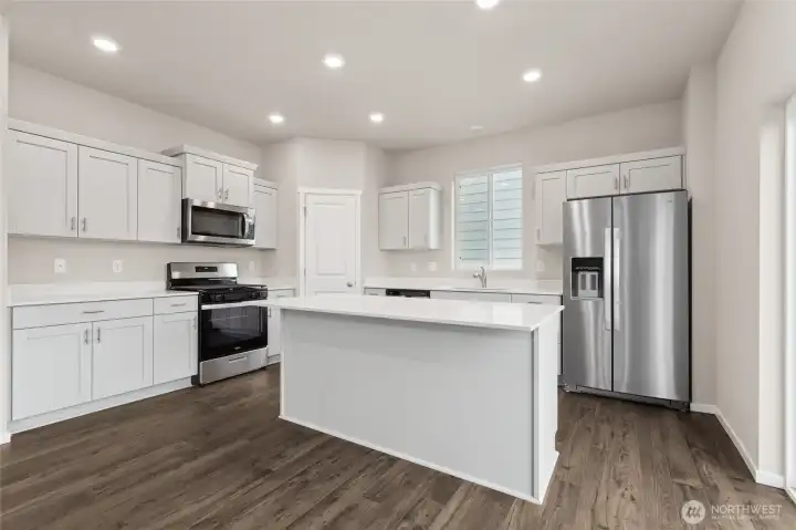 Bright and spacious kitchen featuring white quartz countertops, a center island, stainless steel appliances. Photos are representative only and may display different color packages and/or upgrades. Bright and spacious kitchen featuring white quartz countertops, a center island, stainless steel appliances. Photos are representative only and may display different color packages and/or upgrades.