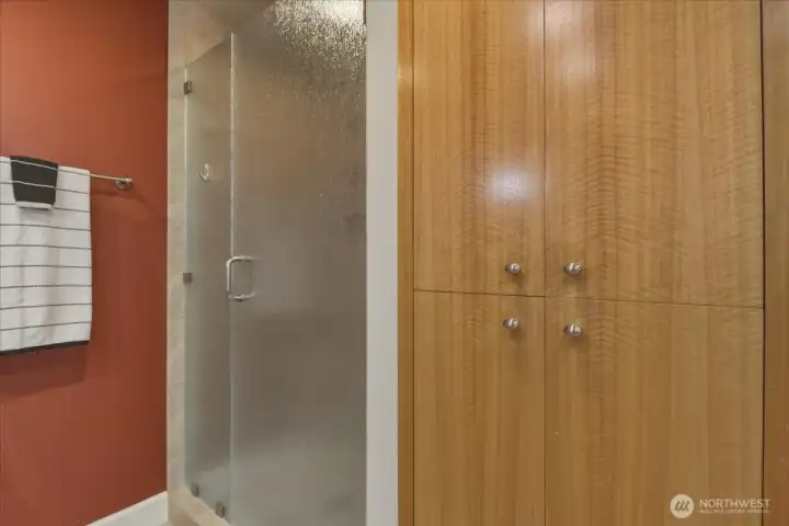 Ensuite primary bath w/ double vanity, tile floor, walk-in tile shower, storage