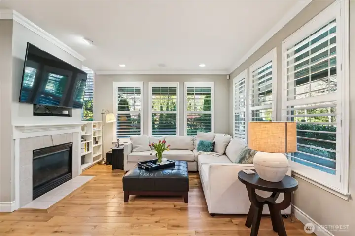 Spacious family room framed by walls of windows with timeless white shutters. Spacious family room framed by walls of windows with timeless white shutters.