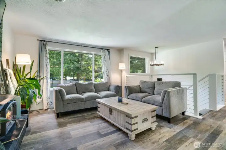 Large picture windows fill the living room with natural light, while fresh paint and vinyl flooring create a clean, cohesive feel throughout the upper floor.