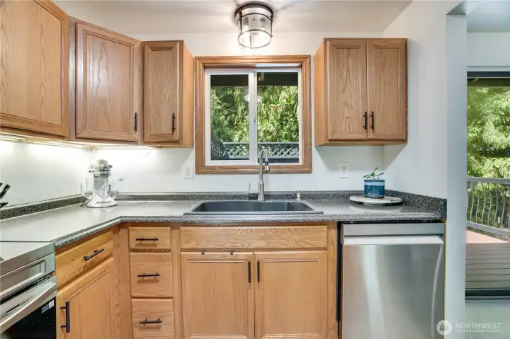 The kitchen boasts oak cabinets with stylish hardware, plenty of counter space, newer paint and a window overlooking the private patio.