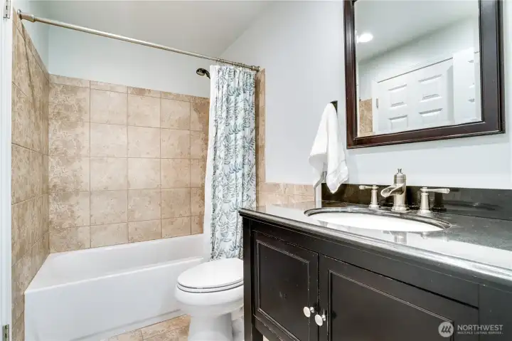 The upstairs full bath has a storage vanity, tile floors and matching tub surround.