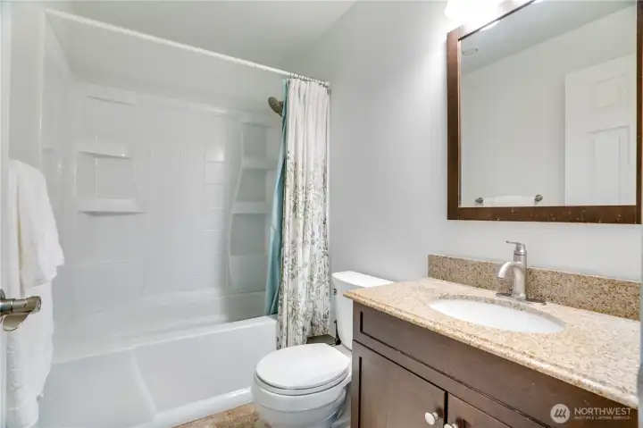 The full bath downstairs has an oversized vanity, shower surround with storage and newer paint.