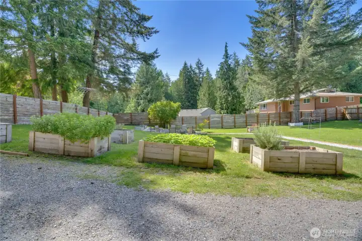 Established garden beds are already producing strawberries, mint, and herbs, with additional space available for gardening, planting, or future projects.