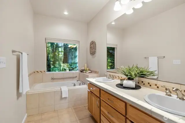 Primary bedroom with picture window framing the beautiful treed greenbelt.