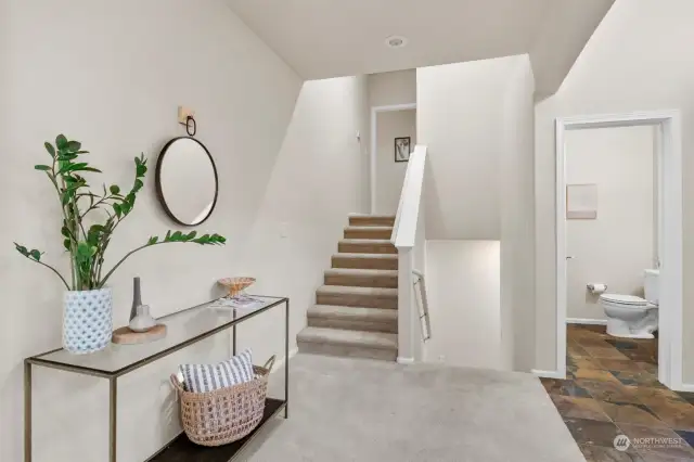 Half bath off of the entry, and stairs leading up to primary bedroom and down to garage-entry level.