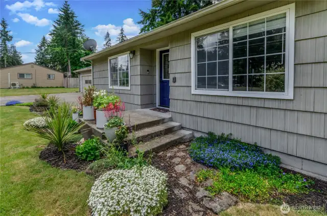 Welcome home! Thoughtfully landscaped with pops of color and a charming blue front door, this entry invites you in with warmth and personality. A perfect first impression every time.
