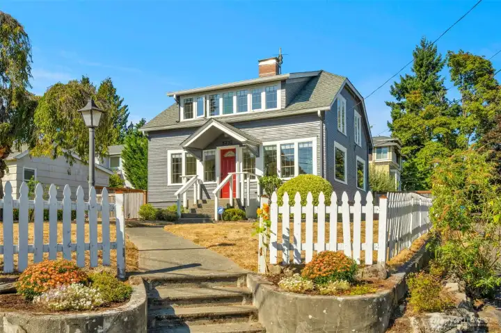 A white picket fence welcomes you to this Seward Park 1922 Craftsman
