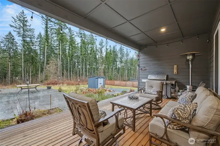 This covered porch overlooks a custom stamped concrete patio and tranquil greenbelt, featuring a dedicated gas line for BBQ, creating a truly turnkey outdoor entertaining space.