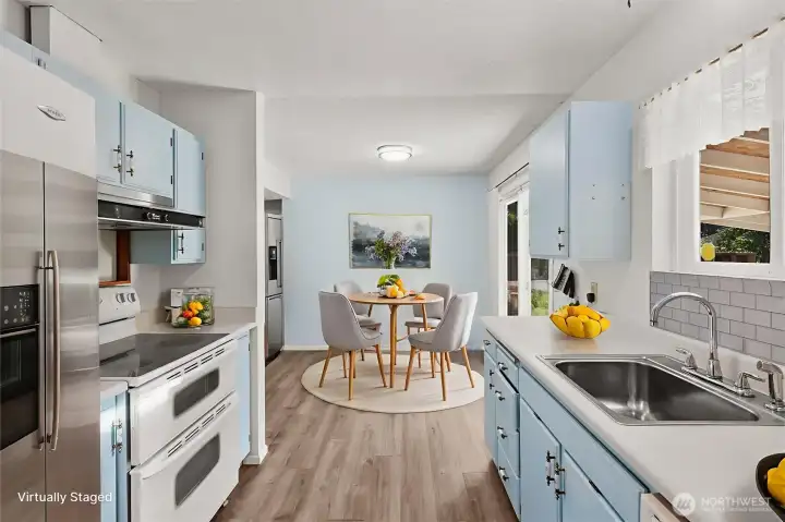 Kitchen features updated LVP flooring and a spacious walk-in pantry and utility room. All appliances stay.