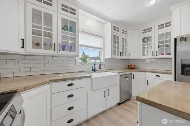 This bright kitchen offers a farmhouse sink, loads of cabinets and ample counter space.