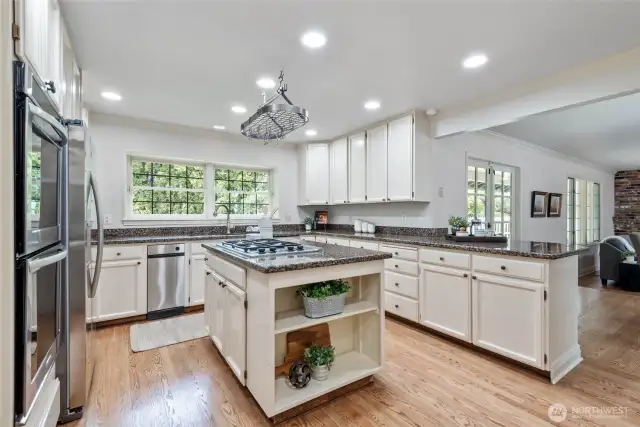 Kitchen with cream cabinets, slab granite counters and stainless appliances.