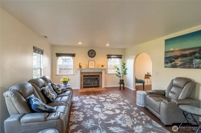 Living room is at the front of the home with wood burning fireplace with mantle. Arched windows and arched door entrance to dining room.