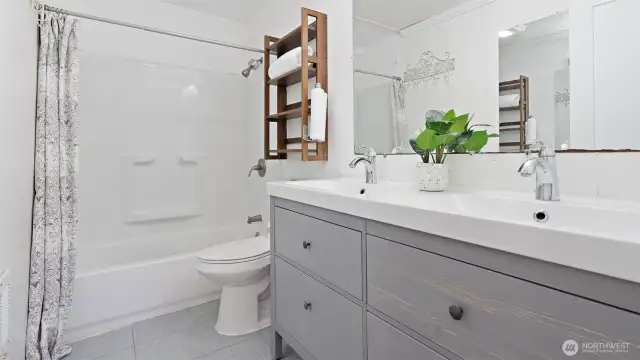 Enjoy the refreshed feel of the lower bathroom! It features recent updates including a new vanity, toilet, tub surround, and stylish flooring.