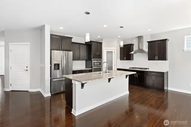 Garage entry door just off of the Chef kitchen with Granite Cooking Island, separate cook top, stainless appliances, all perfect for entertaining guests!