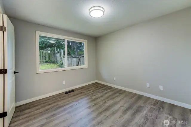 Serene and spacious primary bedroom with a large window overlooking the private backyard.