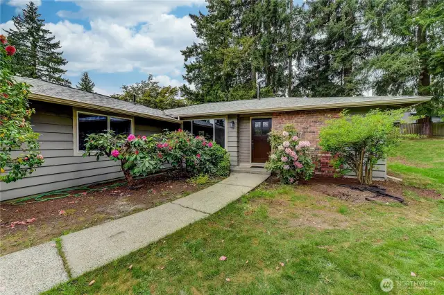 Nestled on a quiet street, this charming rambler boasts a beautifully landscaped front yard framed by mature trees and vibrant blooms.