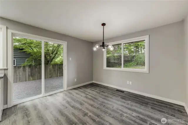 Chic and cheerful dining space surrounded by windows that bring in natural light and lush green views.