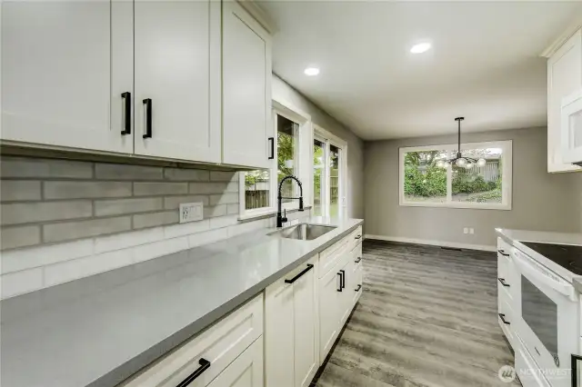 Sleek, modern kitchen featuring crisp white shaker cabinets, elegant quartz countertops, and a stylish subway tile backsplash.