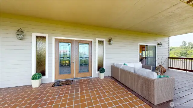 Tiled entry way which extends into interior entry way with double glass doors and outdoor living space.
