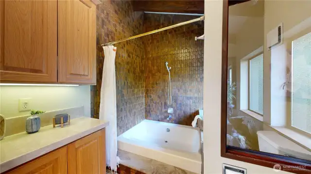 The full bath includes a tiled tub/shower with rich wood-toned surround, creating a cozy spa-like feel just steps from the primary suite.