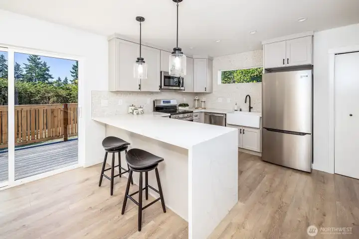 Overhanging kitchen counter can easily accommodate 4 people. Shown here with two.  Additionally, there is space for a dining room table. When touring, notice that the dining space is wired for a chandelier should the buyer choose. Talk to your broker about options for install :)