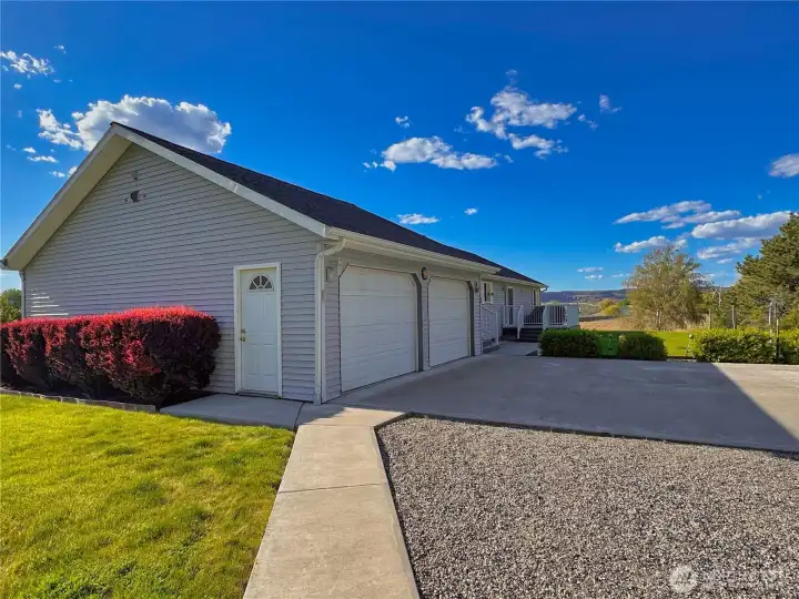 Beautifully landscaped grounds are complemented by a concrete parking area, a walkway to the shop, and a well-maintained gravel driveway.