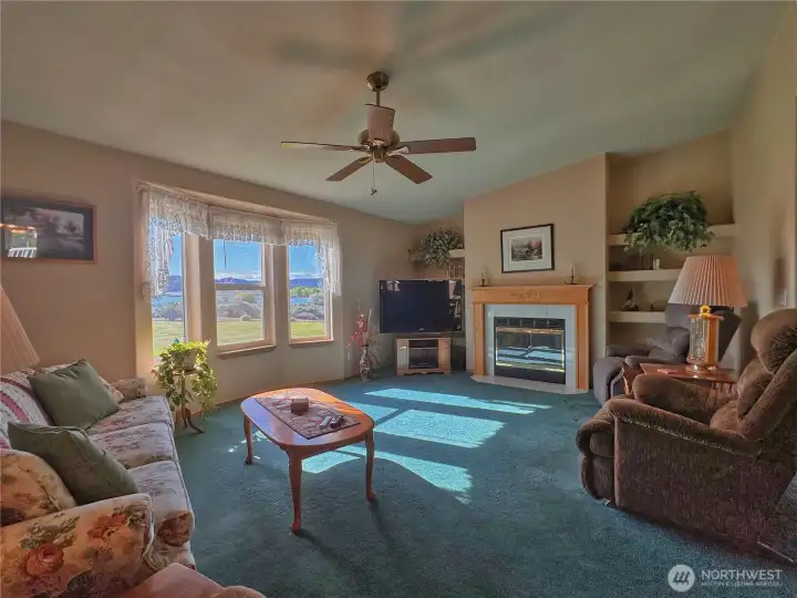 An inviting living room, with sweeping lake views, is centered around a propane fireplace and flanked by symmetrical built-in shelving that adds both style and functional storage.
