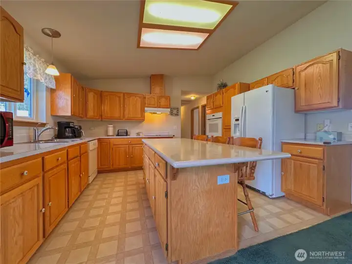 Vaulted ceilings span the living room, dining area, and kitchen, creating an airy, light-filled central living space.