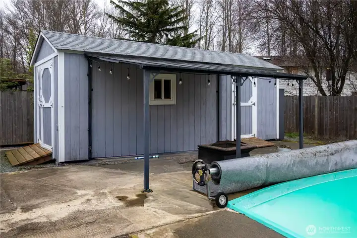 Large utility shed with attached metal awning and firepit. Large utility shed with attached metal awning and firepit.