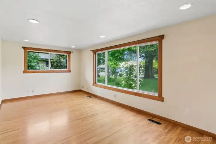 Spacious living room highlighted by oversized windows, natural light, and classic hardwood flooring throughout. Spacious living room highlighted by oversized windows, natural light, and classic hardwood flooring throughout.