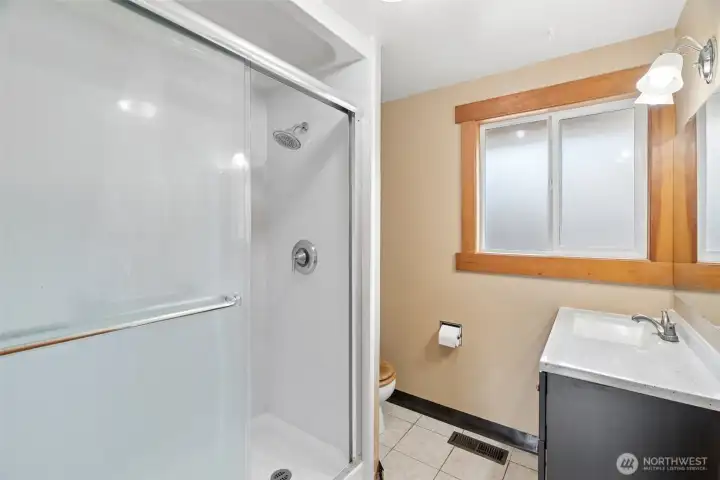 Full bathroom featuring a walk-in shower, vanity storage, and natural light for everyday convenience. Full bathroom featuring a walk-in shower, vanity storage, and natural light for everyday convenience.
