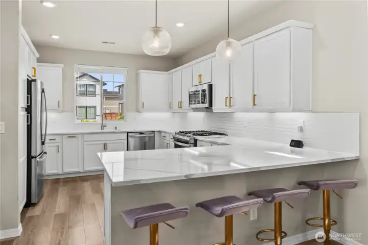 Chefs kitchen with upgraded gas range and quartz counters.