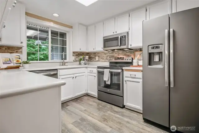Galley kitchen includes LVP    flooring, stainless-steel appliances