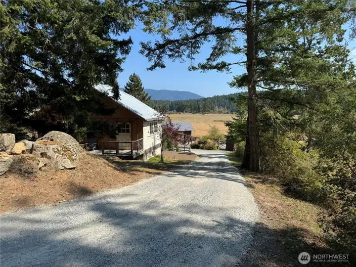 Private driveway runs along the south boundary line, past the storage building to arrive at the Cottage located in the southeast corner of the 2 acre parcel. View tot he east.