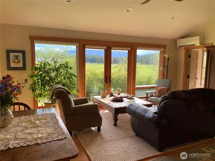 Main living room boasts large windows and french doors looking east, northeast towards he valley and Mount Constitution. Seller's choice was to build decking on the opposite side of the home (see patio photos). Future owner may want to build decking off this side of the house someday, or leave as is.