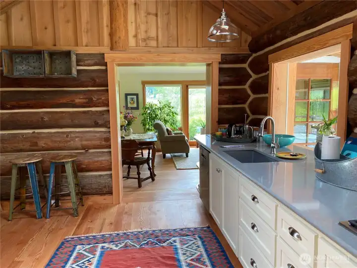 Wide entry into the main living room from kitchen. Local milled fir flooring and trim throughout cottage. The 400 sq ft log cabin was originally built by well known log home builder, Steve Kenady. 600 sq ft of stick built addition was added on in 2020-2022.