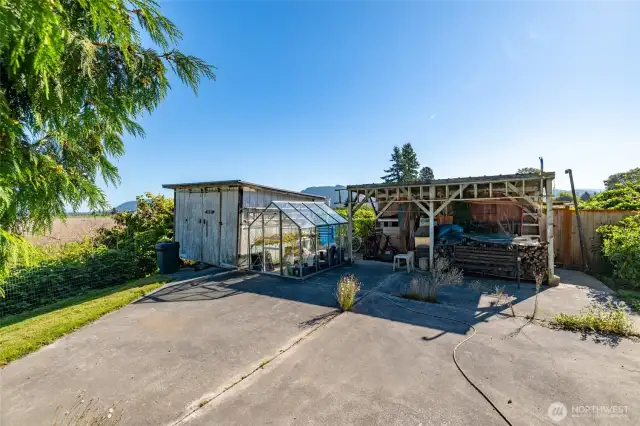 A greenhouse, shed, and lean-to offer storage and year-round growing opportunities.