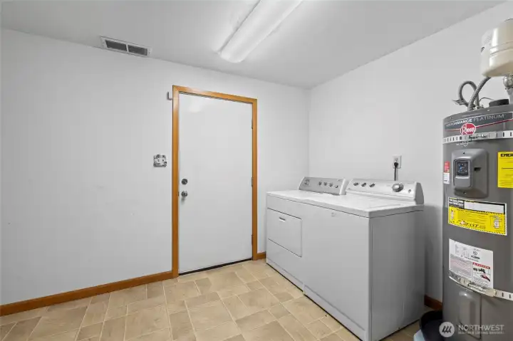 Laundry area located in the basement with a door to the back yard