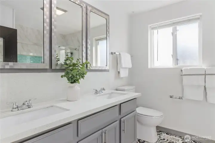 Hall bath with double quartz vanity sinks, and ornate ceramic tile floor.