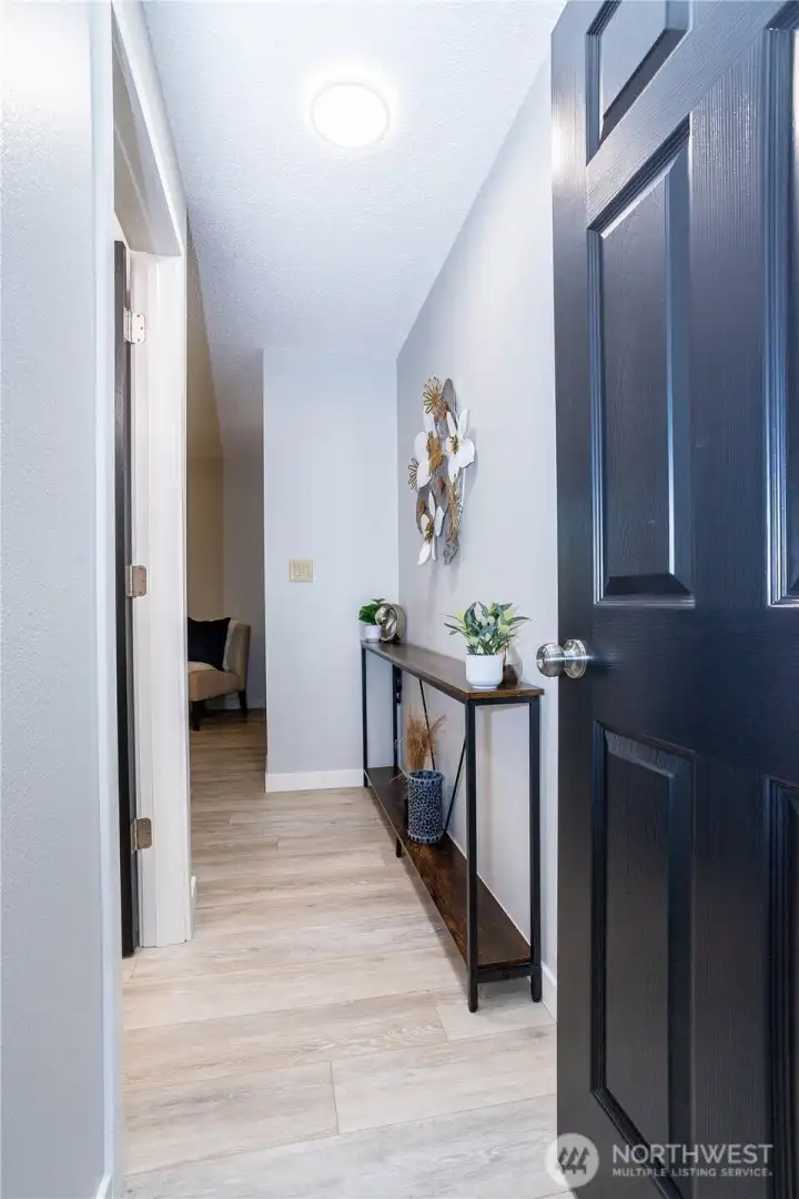 Stepping through the front door, you’re welcomed by a bright, refreshed entry hallway that immediately feels clean and move-in ready. The luxury vinyl plank flooring runs seamlessly through the space, adding durability while keeping the aesthetic modern and cohesive. Neutral wall tones make the area feel open and light, while the darker door finish provides contrast and visual interest. There’s enough wall space for a console table, artwork or a drop zone setup, making the entry both functional and welcoming. It’s the kind of hallway that quietly signals the home has been cared for — tidy, updated and ready for everyday life.